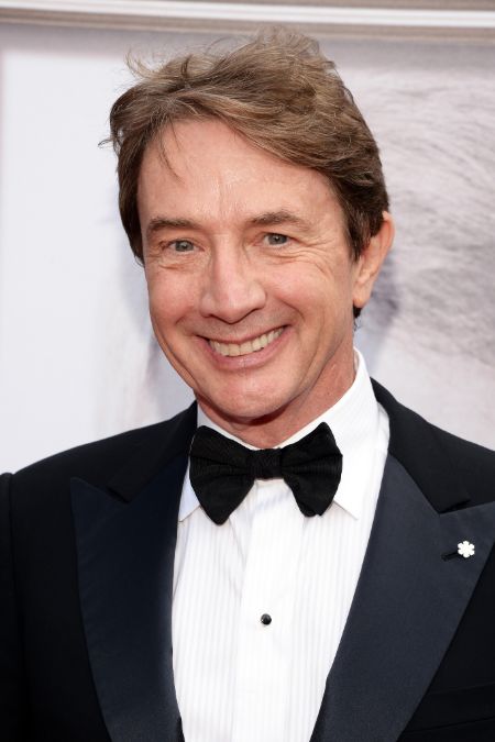 Martin Short in a black suit poses for a picture.